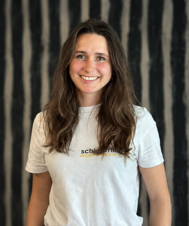 Lächelnde Frau mit langen braunen Haaren, weißes T‑Shirt