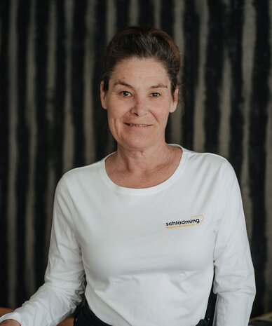 Frau trägt weißes Shirt mit Schladming-Logo, am Geländer stehend.