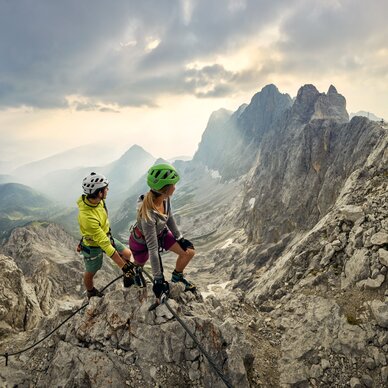 Two climbers wearing helmets on a rocky mountain ridge