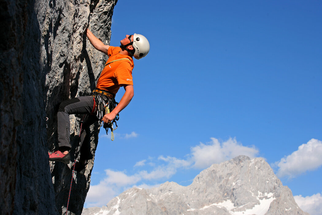 Climber ascending a rocky cliff wearing a helmet