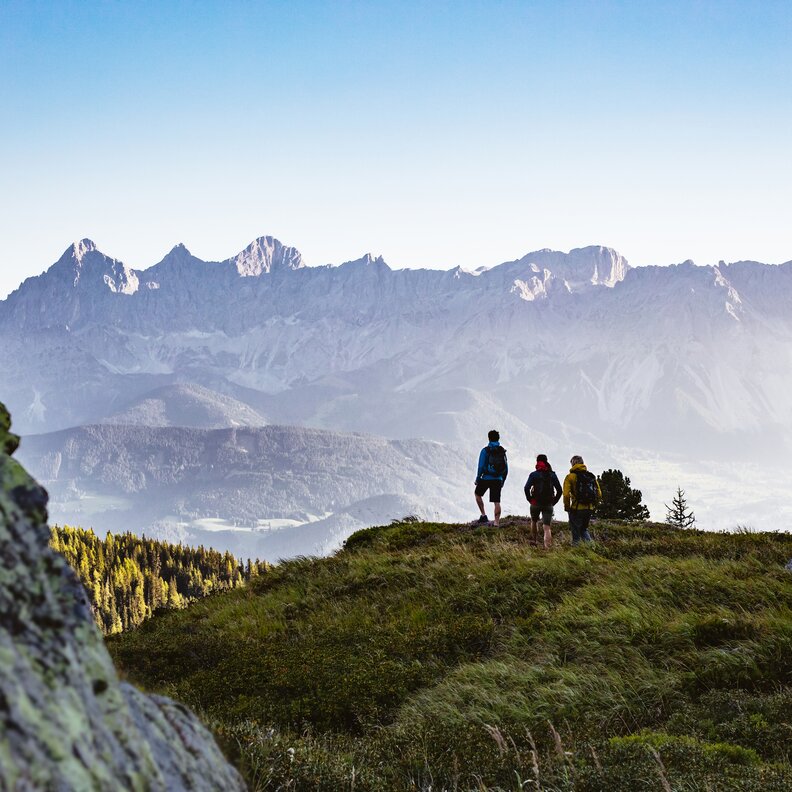 Group of hikers on grassy overlook facing distant mountains | © Sebastian Stiphout