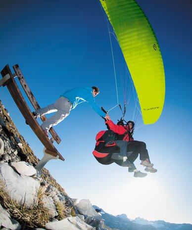 Two paragliders on rocky slope during takeoff.