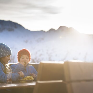 Zwei Kinder in Winterjacken essen Pommes im Freien. | © Claudia Ziegler