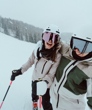 Two skiers in helmets and goggles on snowy slope