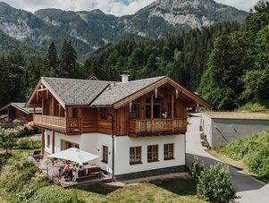 Holz-Chalet in der Alpenlandschaft mit Terrasse und Gästen