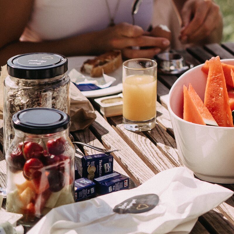 Outdoor breakfast table with fruit, jams, juice and bread