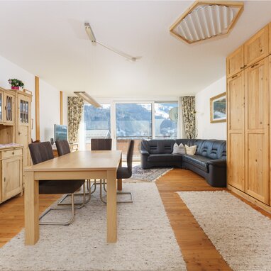 Living room with wooden furniture, dining table, and leather sofa