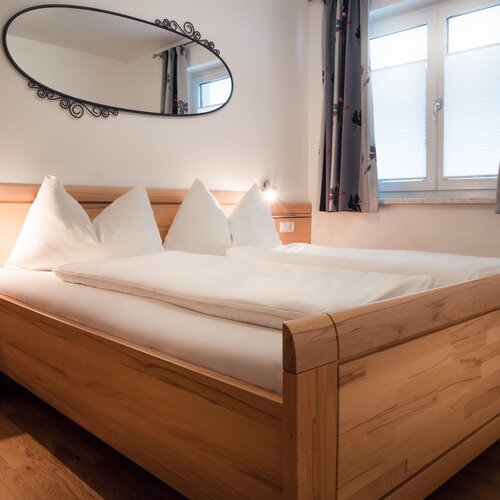 Wooden bed with white linens and pillows in bedroom