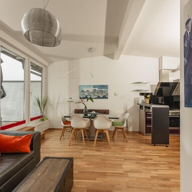 Offener Wohnbereich mit Sofa, Esstisch und großen Fenstern