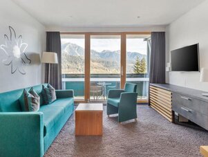 Living room with teal sofa, chairs, and mountain view. | © Sarah Kurre