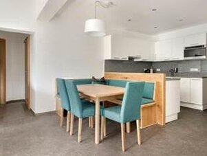 Open-plan kitchen with wooden dining table and teal chairs