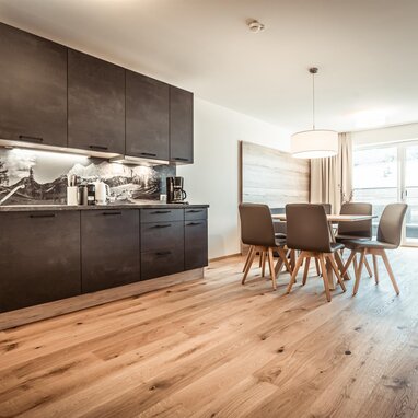 Offene Küche mit dunklen Schränken und Esstisch