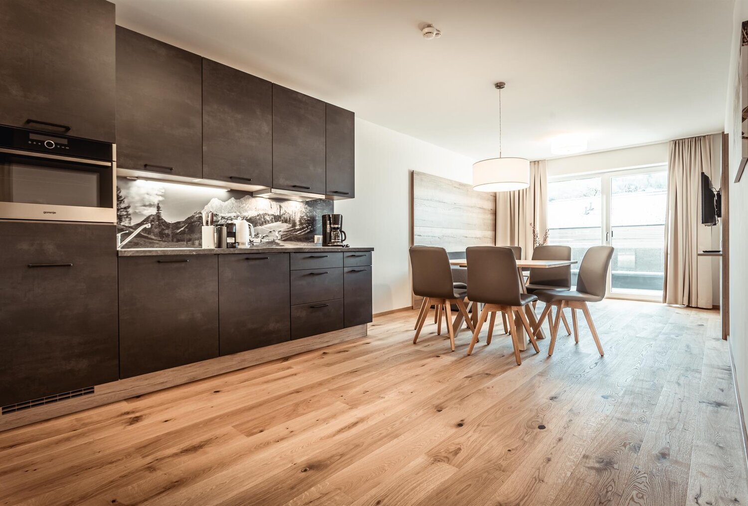 Offene Küche mit dunklen Schränken und Esstisch