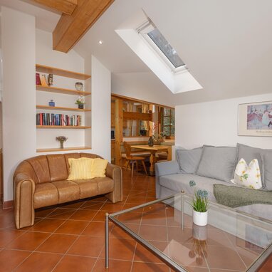 Helles Wohnzimmer mit Dachfenster, braunem Ledersofa und grauem Sofa