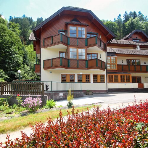 Chaletartiges Gebäude mit mehreren Holzbalkonen umgeben von Bäumen