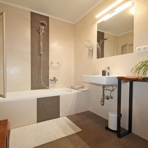 Modernes Badezimmer mit Badewanne, Dusche, Waschbecken und Pflanze. | © SCHLADMING-APPARTEMENTS