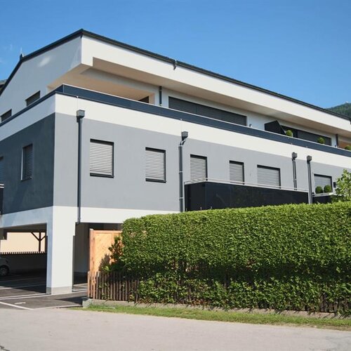 Modern gray and white apartment building with hedge