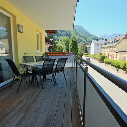 Balcony with outdoor table and chairs overlooking a street and mountains