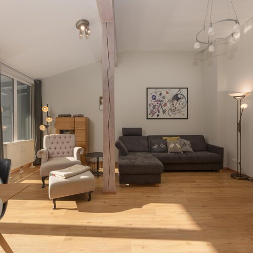 Bright living room with gray sofa, armchairs, and large windows.