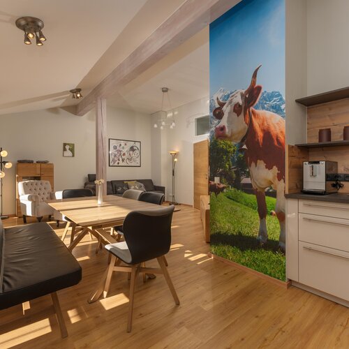 Open-plan living and dining area with cow mural