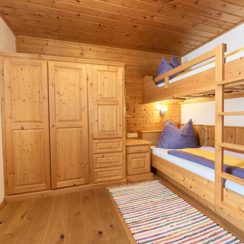 Cozy wooden bedroom with bunk bed and wardrobe