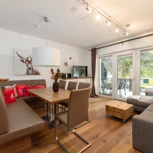 Modern living room with dining table, sofa, and large glass doors