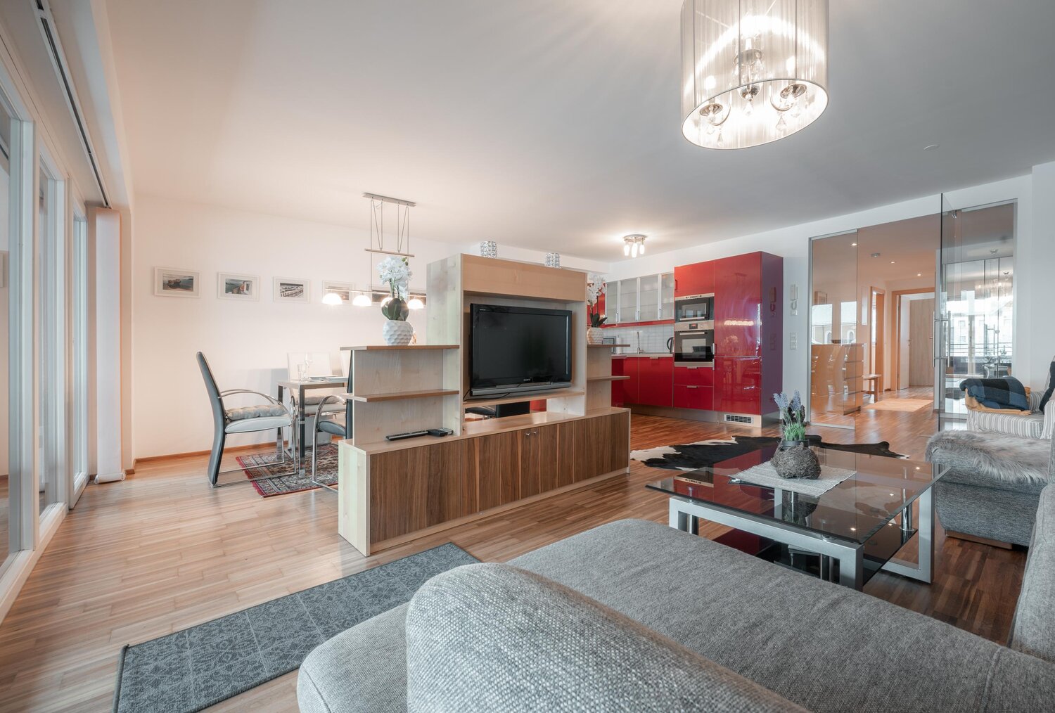 Offener Wohnbereich mit roter Küche und Essbereich | © TIEBER