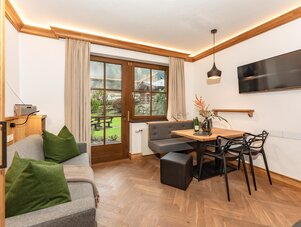 Wohnzimmer mit Holzboden, Esstisch und Gartenblick.