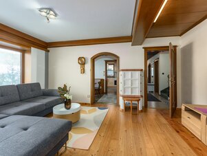 Cozy living room with gray sectional sofa, wooden floors, and ceiling beams