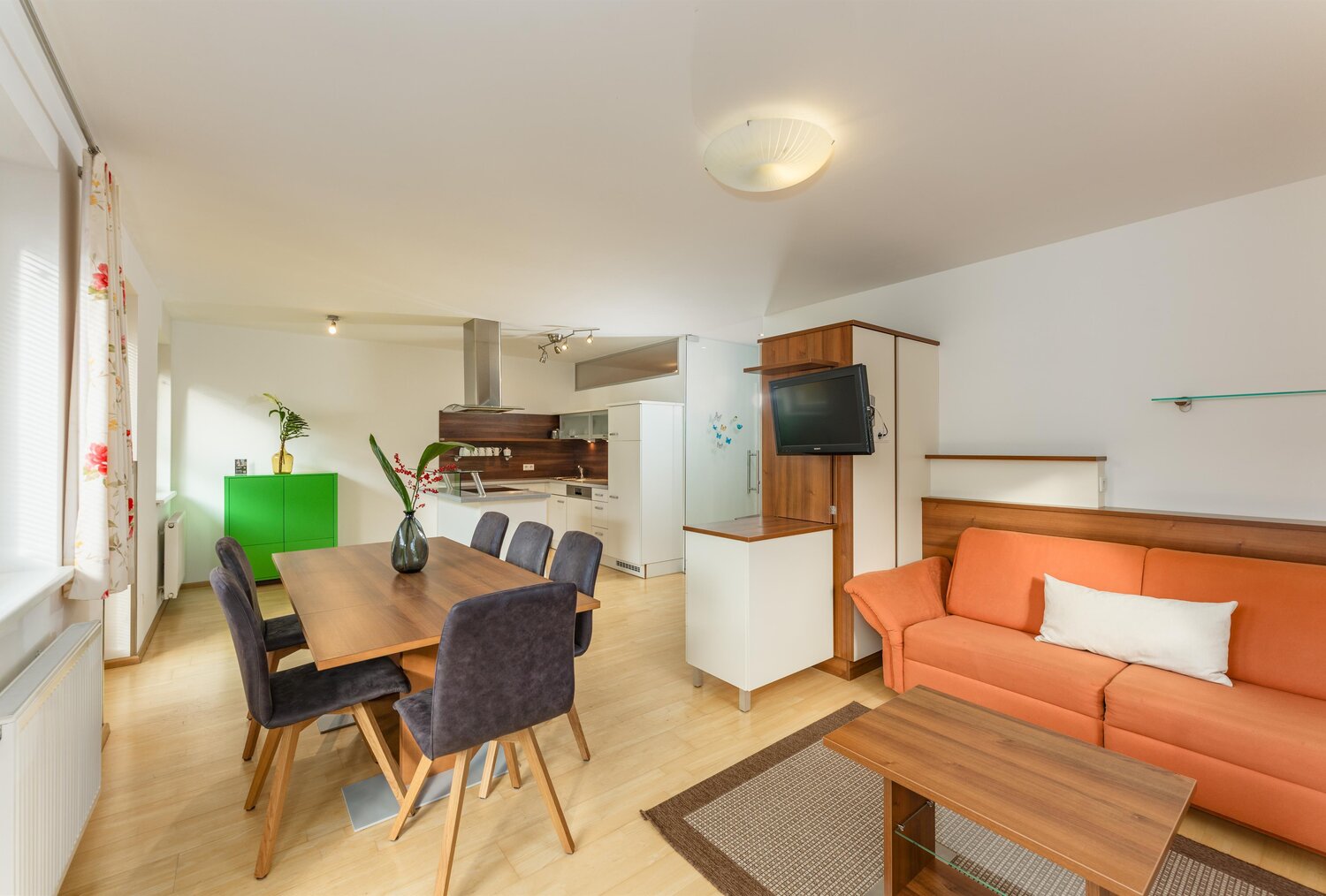 Open-plan living area with orange sofa and dining table