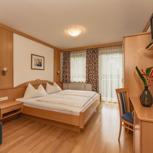 Hotel room with wooden furniture, double bed, desk and TV