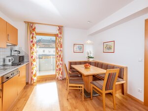 Bright kitchen and dining area with wooden furniture and balcony door