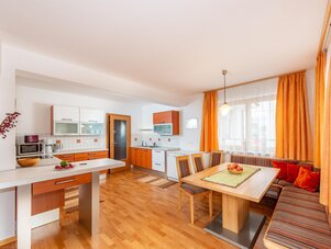 Bright open-plan kitchen and dining area with orange curtains