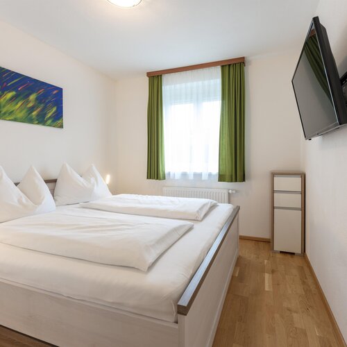 Bright hotel-style bedroom with white bedding and green curtains