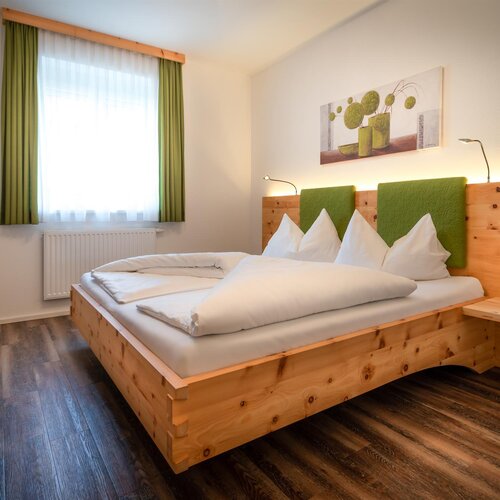 Wooden bed with green headboard in hotel room