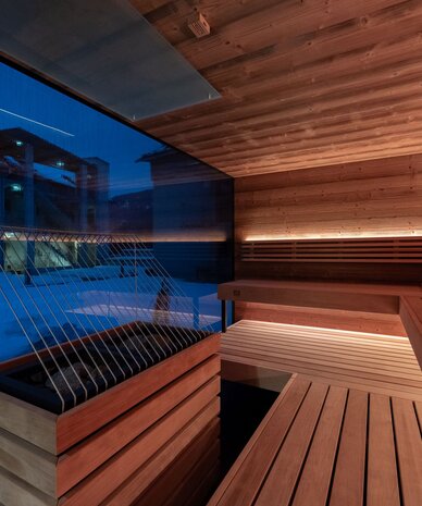 Holzsauna-Innenraum mit Bänken und Glaswand
