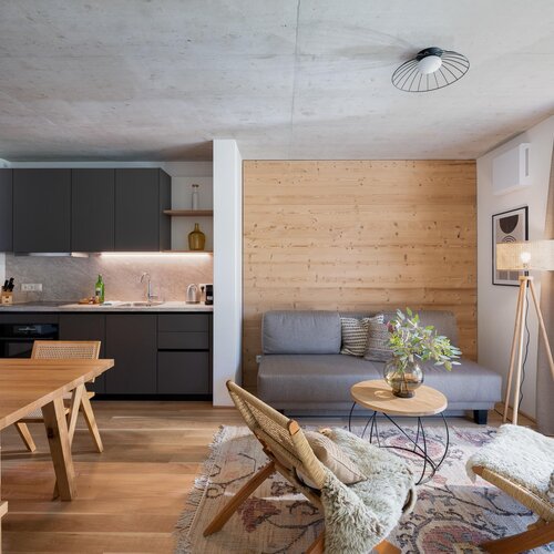 Offener Wohnbereich mit Küche, Holzwand und Sitzgelegenheiten