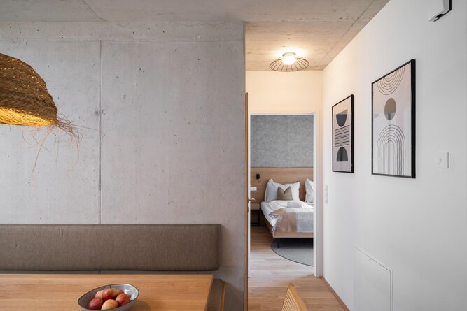 Modernes Wohnambiente mit Essbereich, Betonwand und Durchgang zum Schlafzimmer