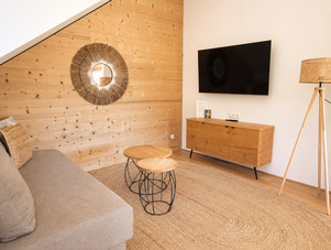 Cozy living room with wooden wall, sofa, and round coffee tables.
