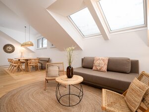 Bright loft living area with skylights, sofa, and wicker furniture.
