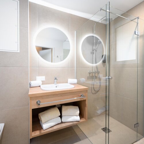 Modernes Badezimmer mit Glasdusche und runden Spiegeln