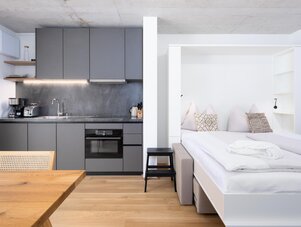 Modern studio with gray kitchen and white bed