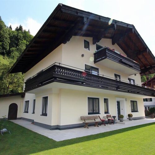 Three-story Alpine house with wide balconies on a green lawn
