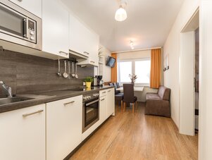 Modern kitchen with white cabinets and dining nook by window.