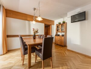 Wooden dining table with brown upholstered chairs in bright dining room