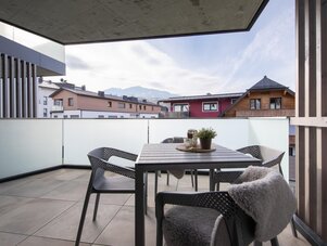 Modern balcony with outdoor table and chairs, frosted glass railing