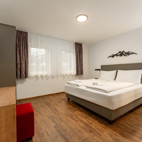 Hotelzimmer mit Kingsize-Bett, zwei Nachttischen und Fenster