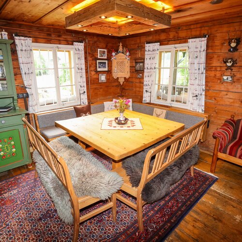 Gemütlicher rustikaler Blockhaus-Essbereich mit Holzwänden, Holztisch und Bänken.