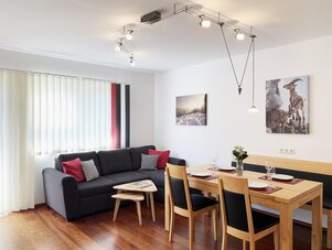 Modern living and dining area with sofa and wooden table.
