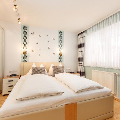 Hotel bedroom with large bed, beige headboard, two nightstands